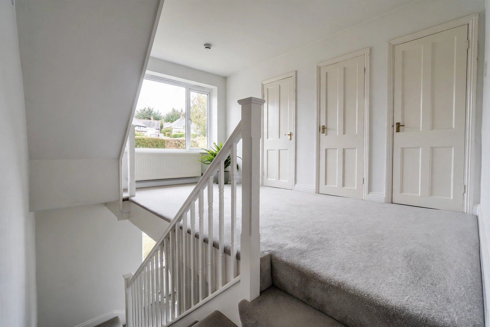 Carpeted staircase and landing with light grey carpet in a UK three-bedroom house