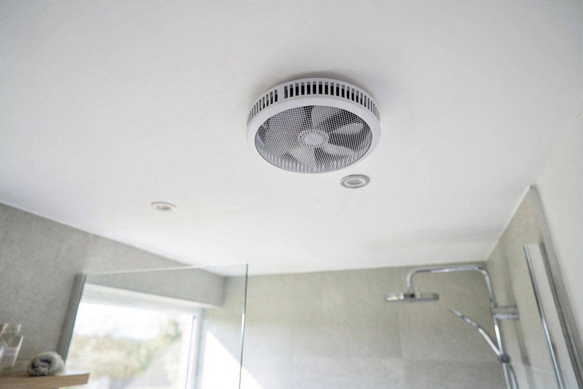 Modern UK bathroom ceiling with a round extractor fan vent above the shower area