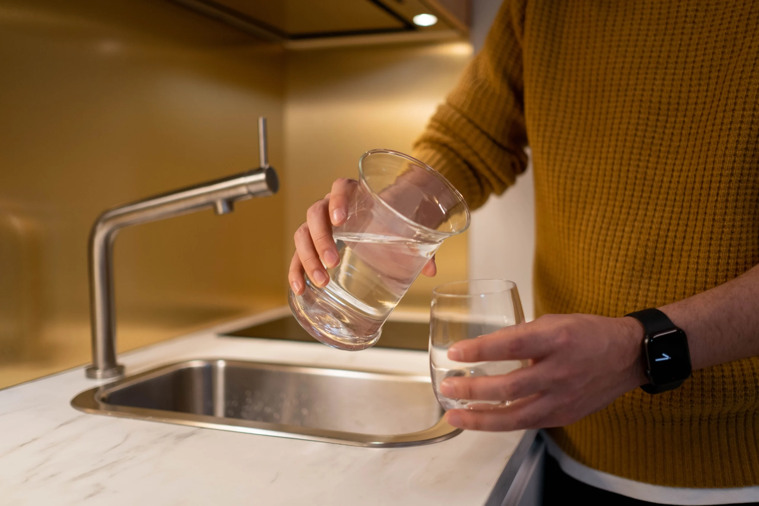 pouring filtered water from pitcher into glass in kitchen